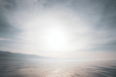 body of water under white clouds during daytime